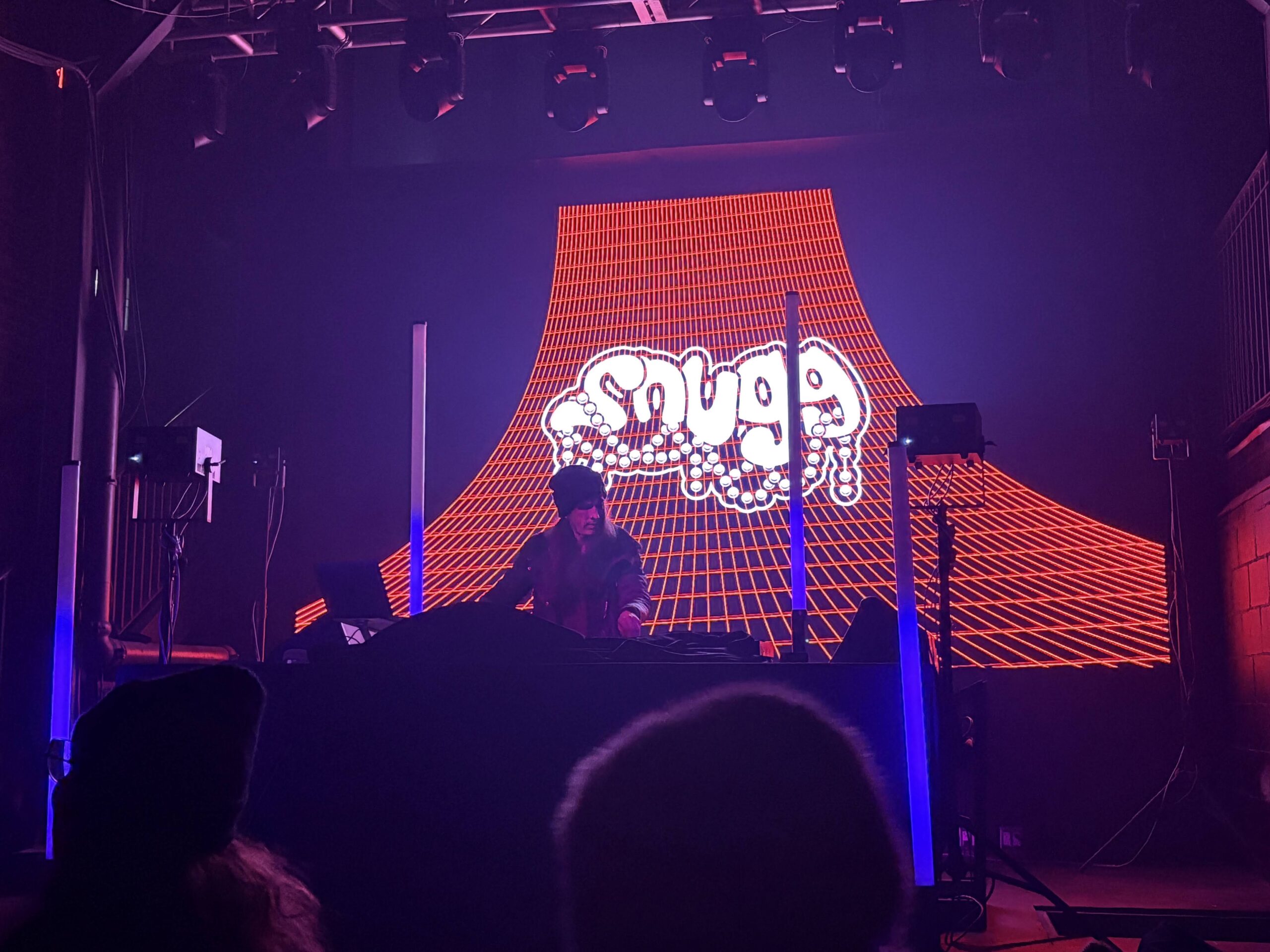 SNUGG performing live in front of a lit stage backdrop