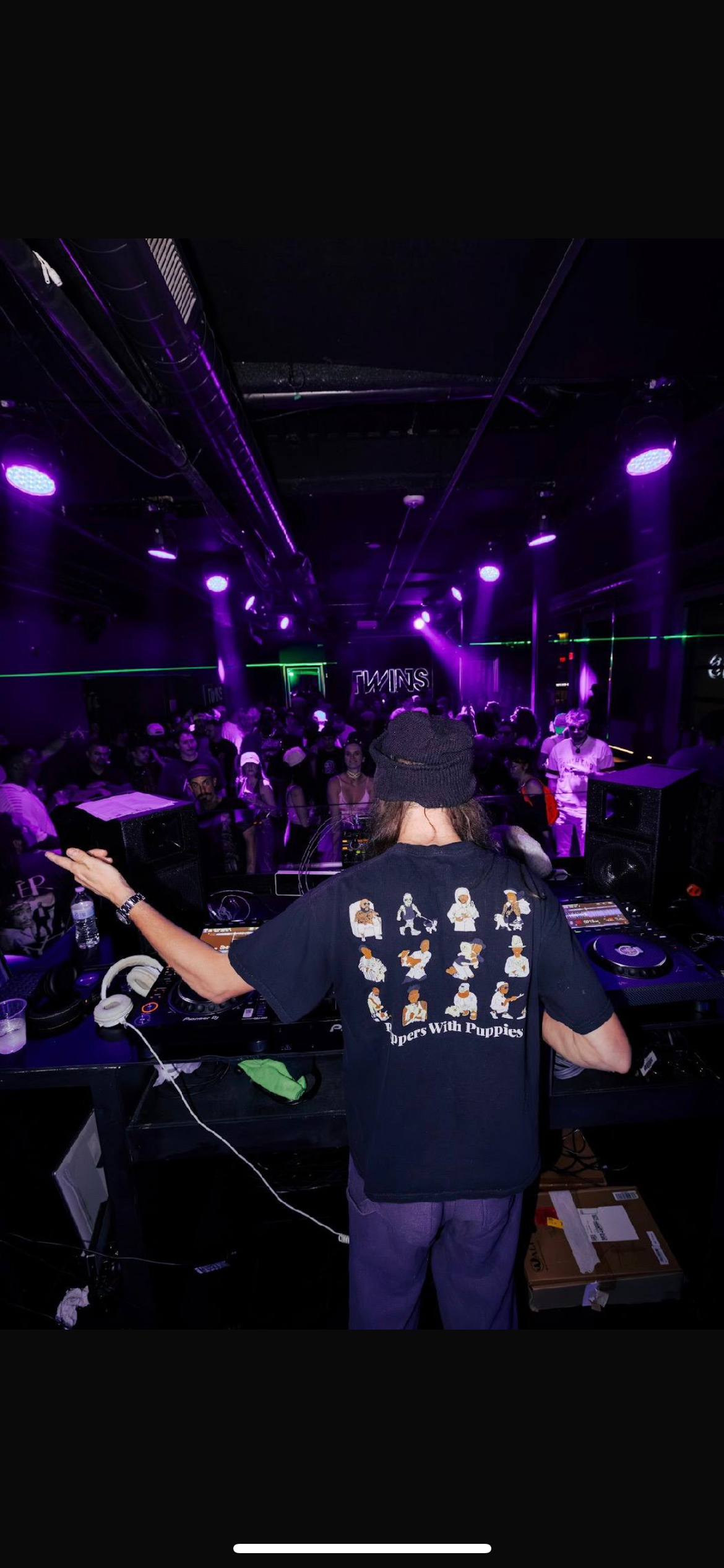 SNUGG behind the decks facing the crowd under purple club lighting